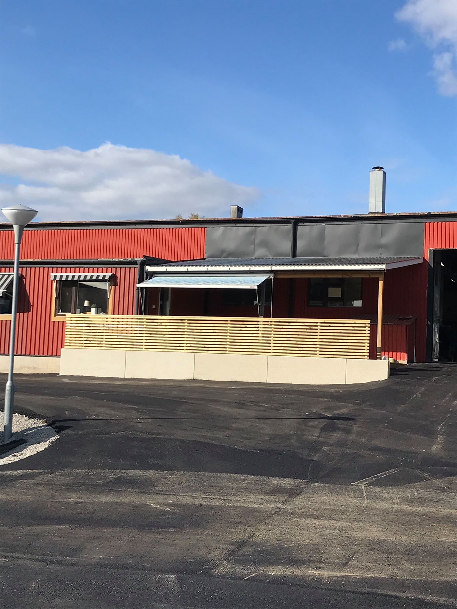Red building with a wooden railing and awning on a clear, sunny day.