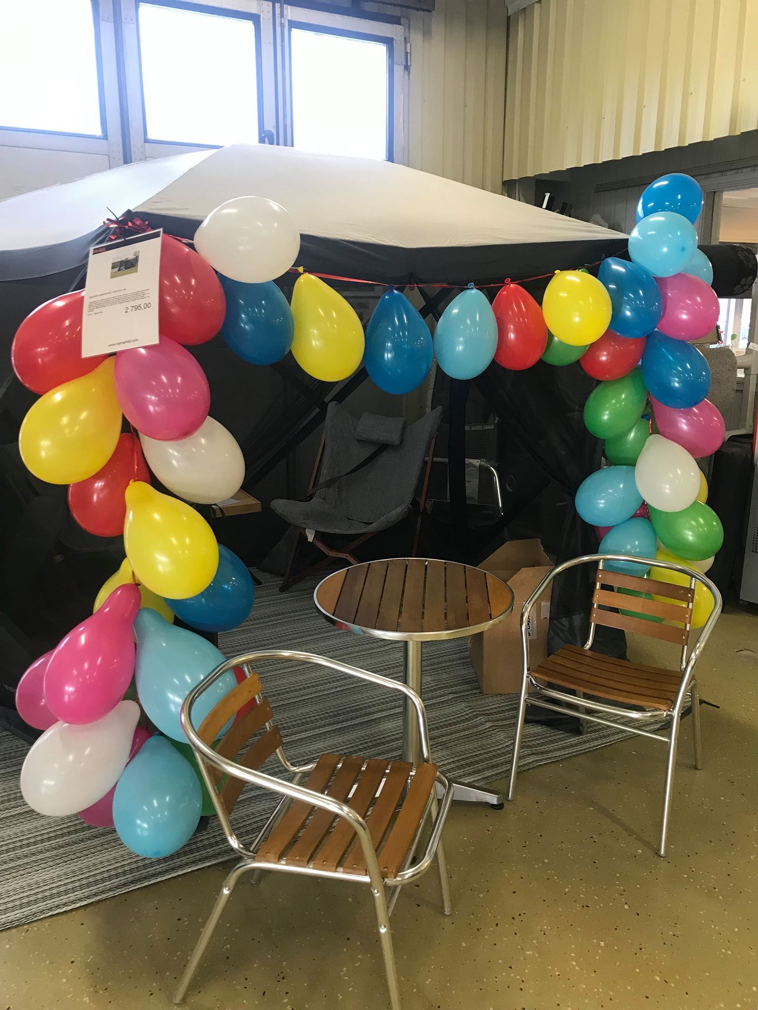 Colorful balloon arch over outdoor-style table and chairs.