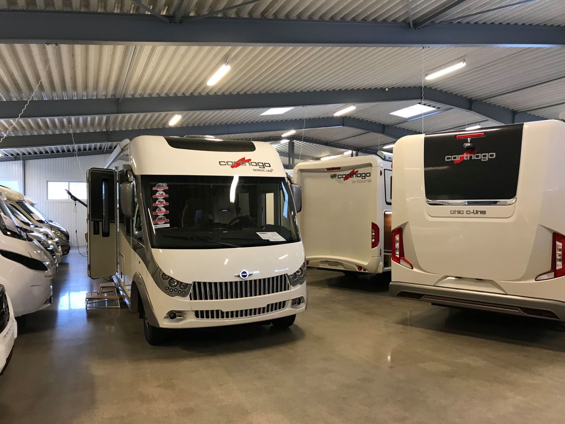 White RVs parked inside a large, bright warehouse.