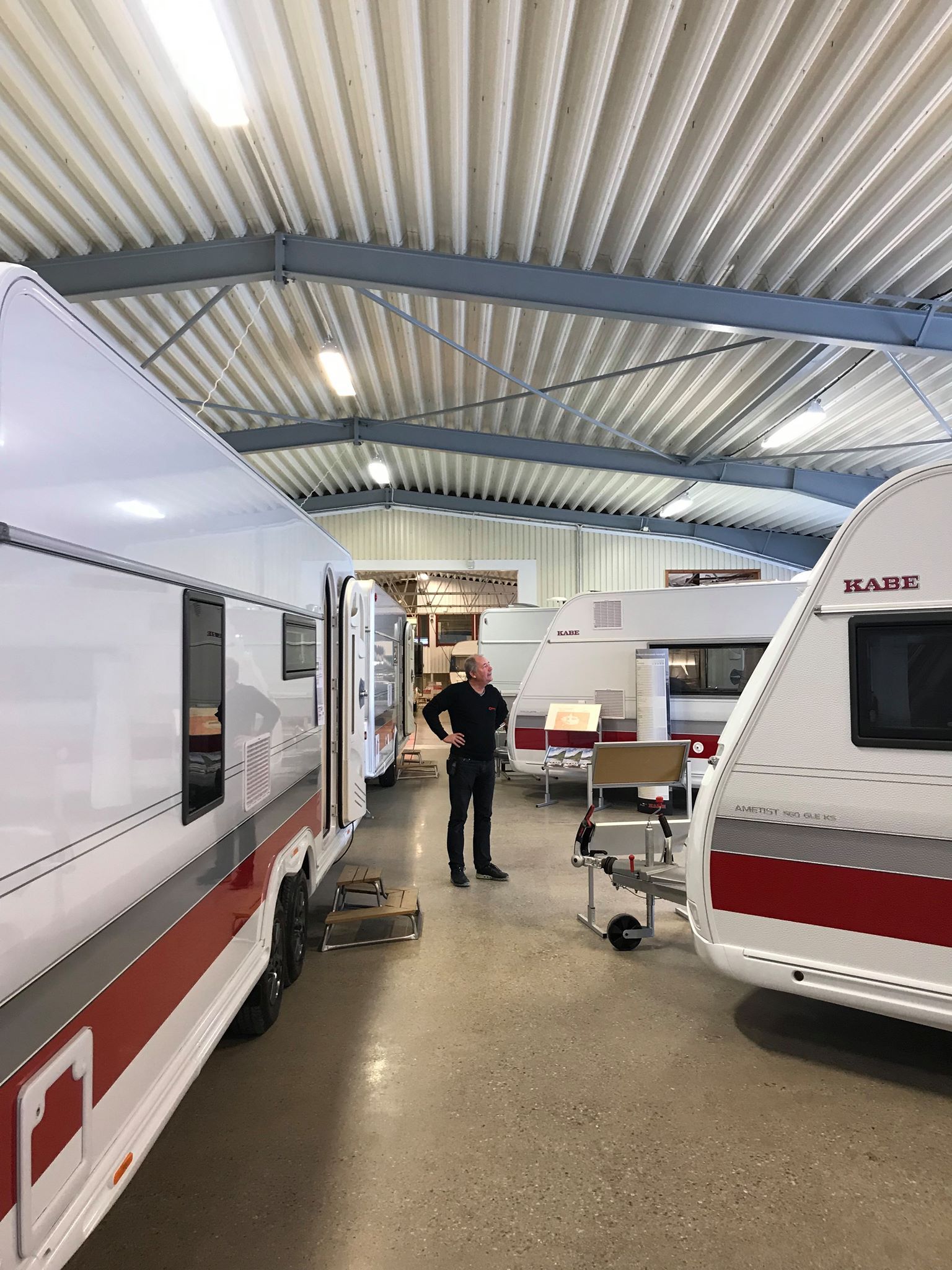 A person stands in a large building with several white and red RVs.