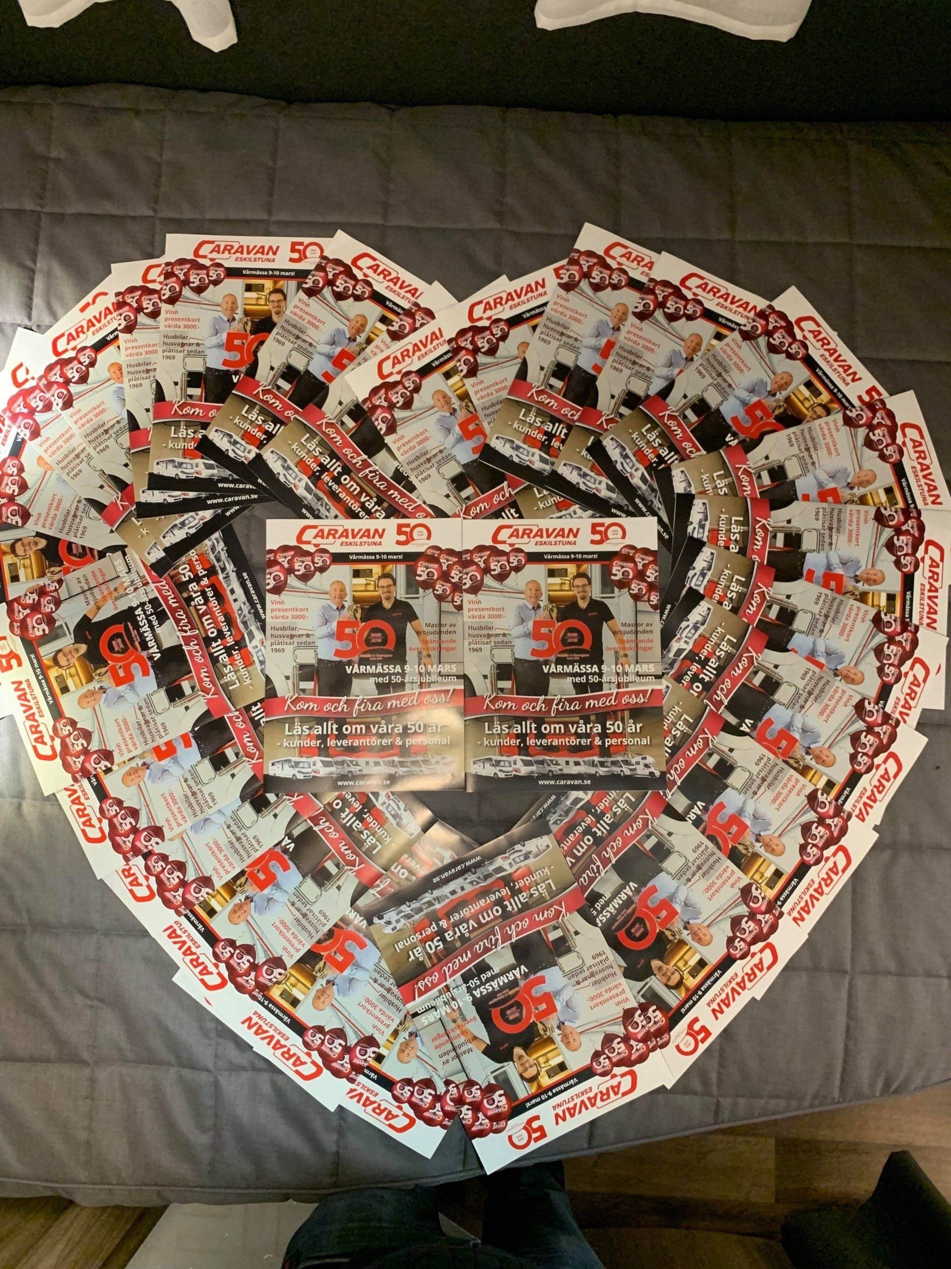 Heart-shaped arrangement of flyers with red, white, and black design, the center flyers display 