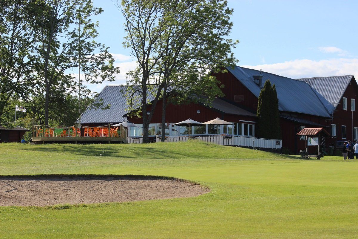 Golf course with a red building and a grassy area with a sand trap.