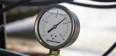 A close-up of a pressure gauge with a needle indicating 15 bar.