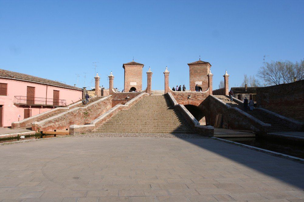 Backsteinbrücke mit Treppen und zwei Türmen in Comacchio, Italien, an einem sonnigen Tag.