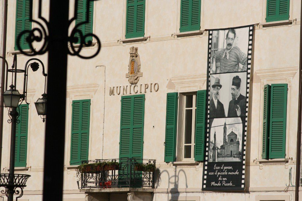 Gebäude mit grünen Fensterläden und „MUNICIPIO“-Schild, darüber ein Banner mit Filmstills.