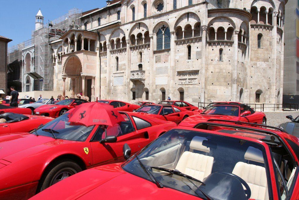 Rote Ferrari-Sportwagen, die vor einem großen Steingebäude geparkt sind, wahrscheinlich in Italien.