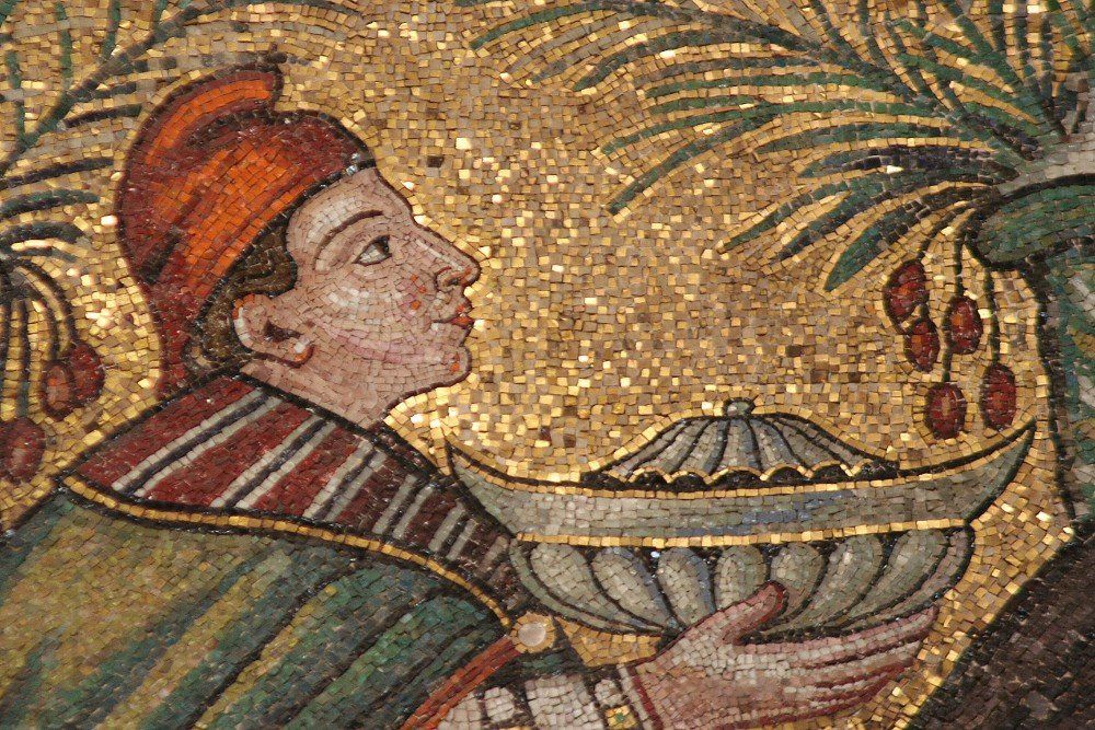 Mosaik eines Mannes mit orangefarbenem Hut und grünem Gewand, der eine Schüssel hält, mit Palmen und goldenem Hintergrund.