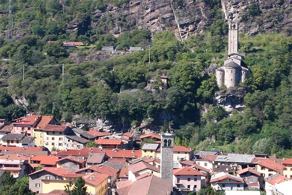 Ein Blick auf ein Dorf mit orangefarbenen Dächern, einer Kirche auf einem Hügel und einer felsigen Klippe.