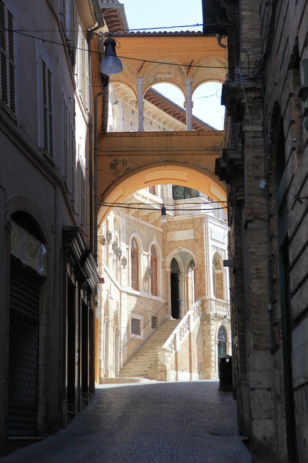 Schmale Straßenperspektive auf Gebäude in Italien mit gewölbten Strukturen und Steintreppen.