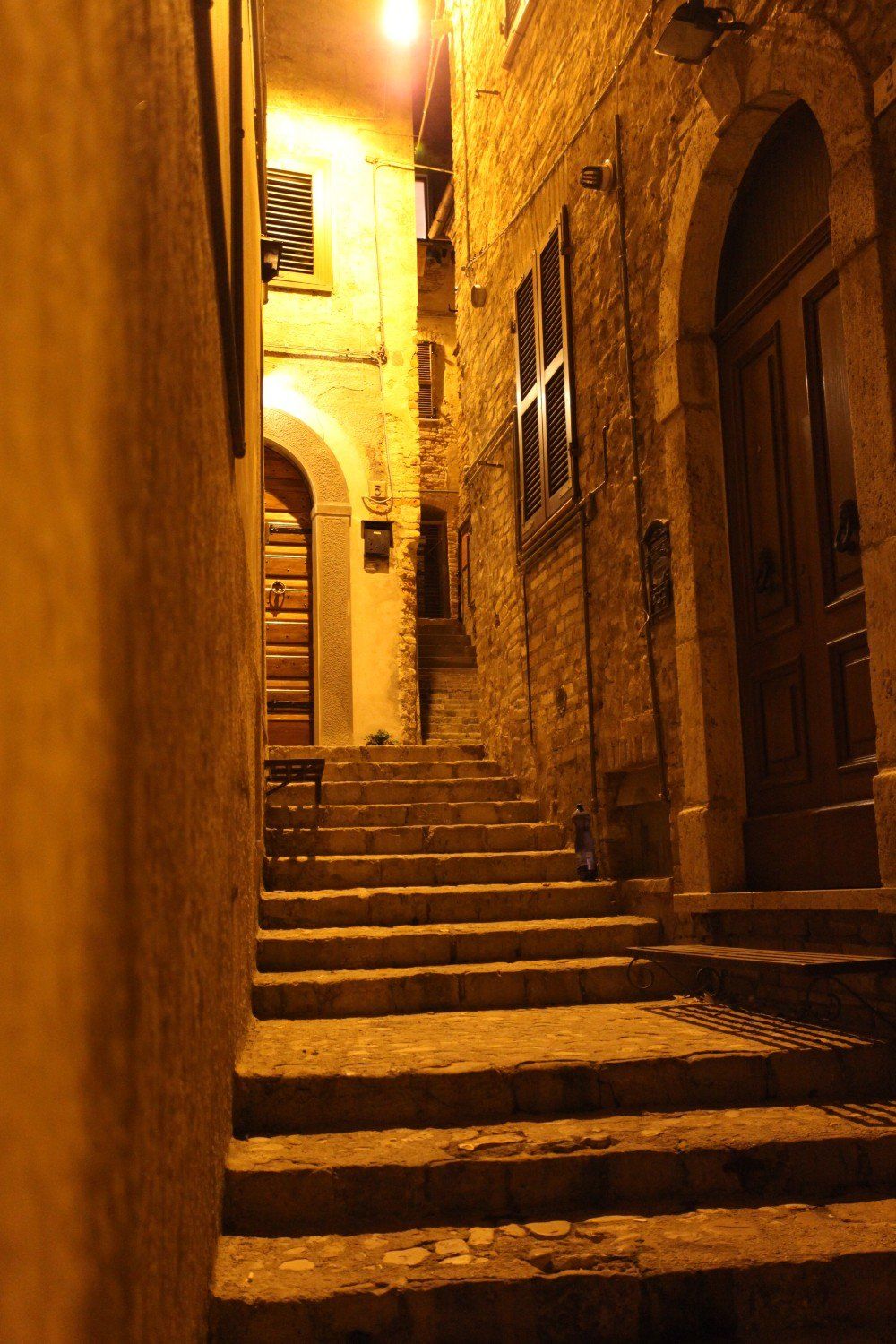 Schmale Steintreppe in einer warm beleuchteten Gasse zwischen Backsteingebäuden, die nach oben führt.