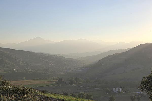 Dunstige Berglandschaft mit Tal, sanftem Licht und fernen Gipfeln.