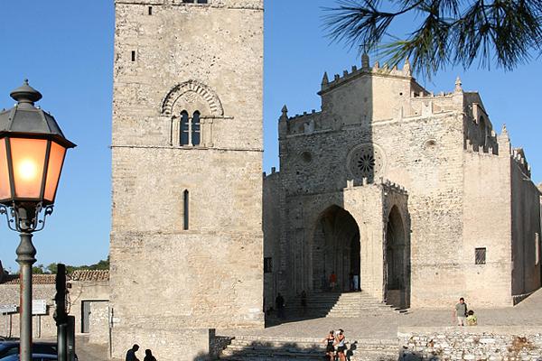 Eine hohe Steinkirche mit Turm in Erice, Sizilien, mit einem Laternenpfahl im Vordergrund. 