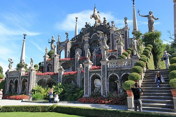 Ein gestufter Barockgarten auf der Isola Bella in Italien mit Statuen, Brunnen und Stufen vor einem blauen Himmel.