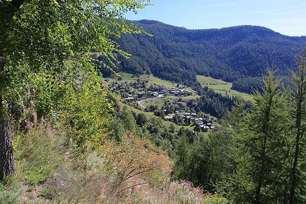 Ein Dorf, eingebettet in ein Tal, umgeben von üppig grünen Bergen und Bäumen