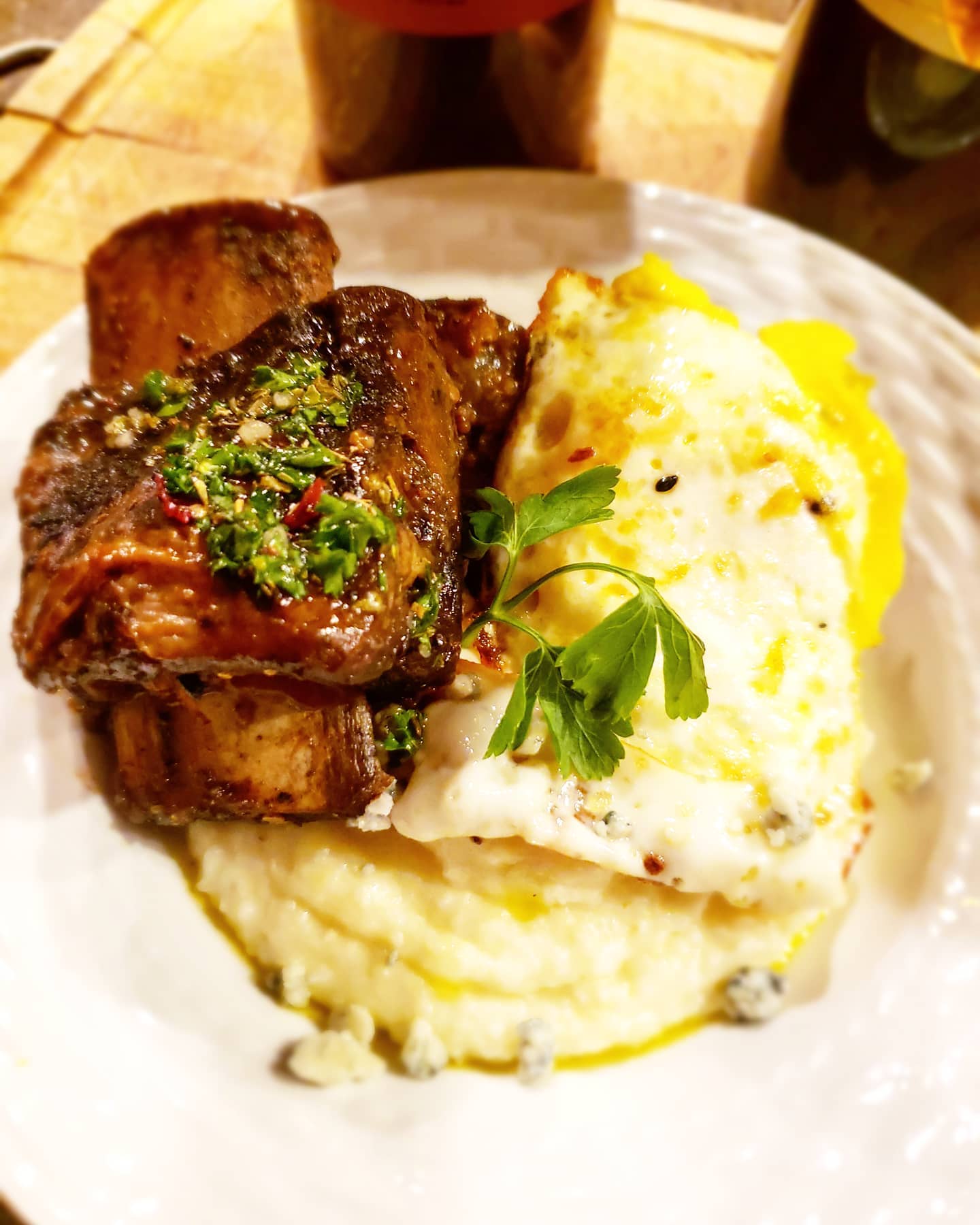 Plate of food: braised short ribs with herb sauce, fried egg, mashed potatoes.