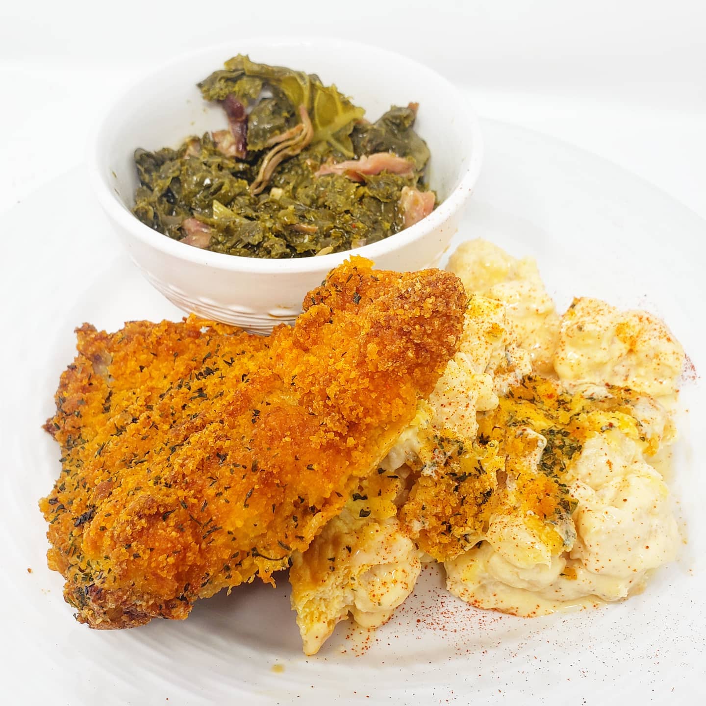 Fried chicken, mac and cheese, and collard greens on a white plate.