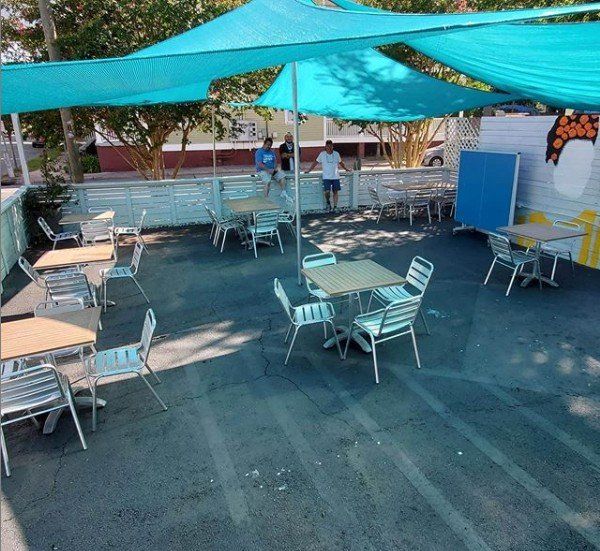 A patio with tables and chairs under blue umbrellas