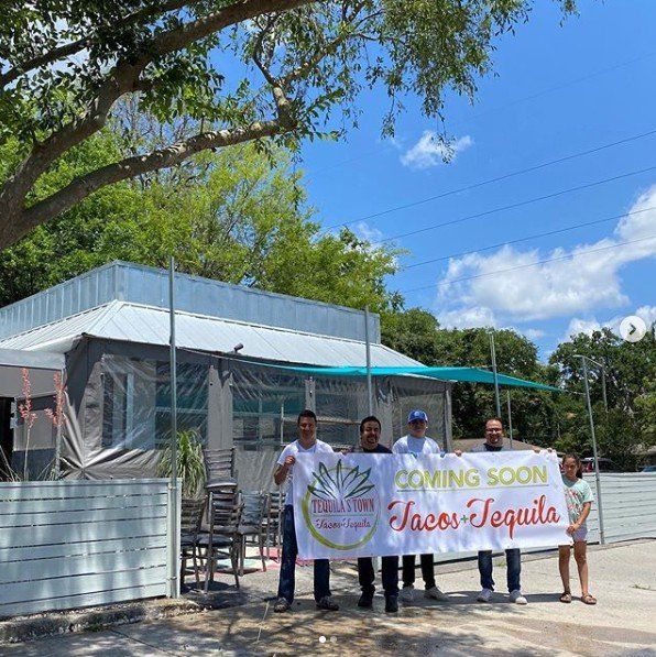 A group of people holding a sign that says tacos tequila