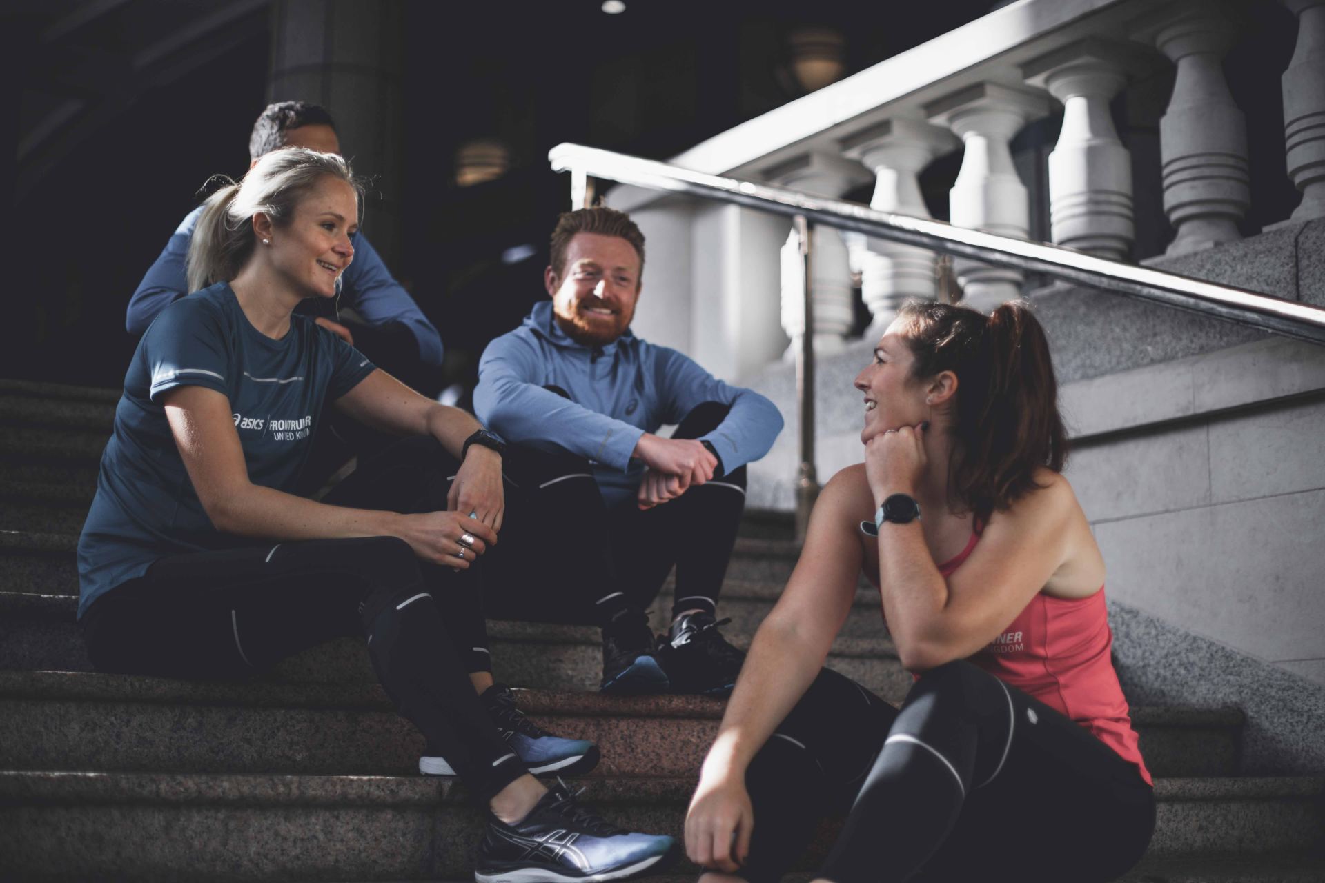 A group of people are sitting on stairs talking to each other.