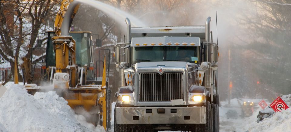 A large truck is driving down a snowy street.