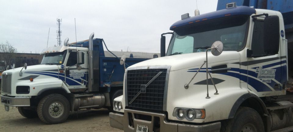 Two volvo dump trucks are parked next to each other