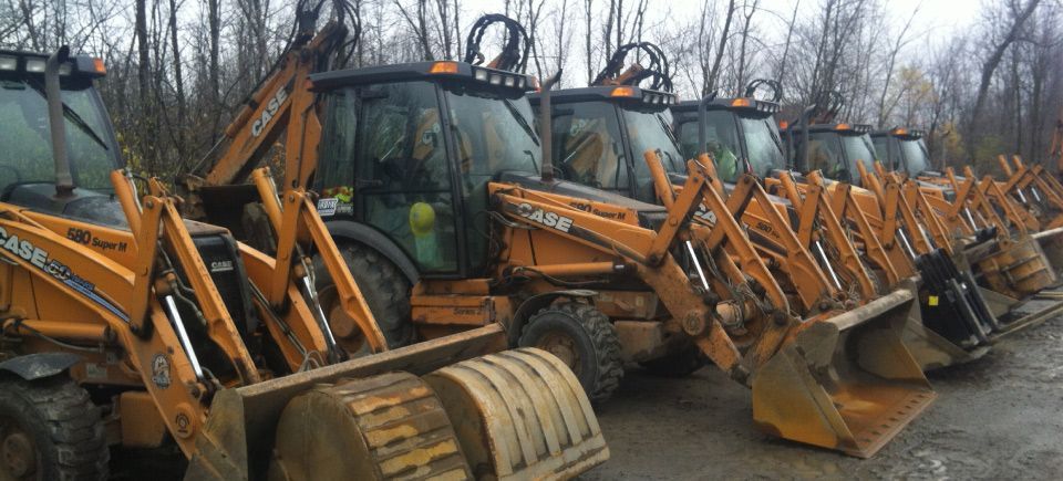 A row of tractors parked next to each other on a dirt road.