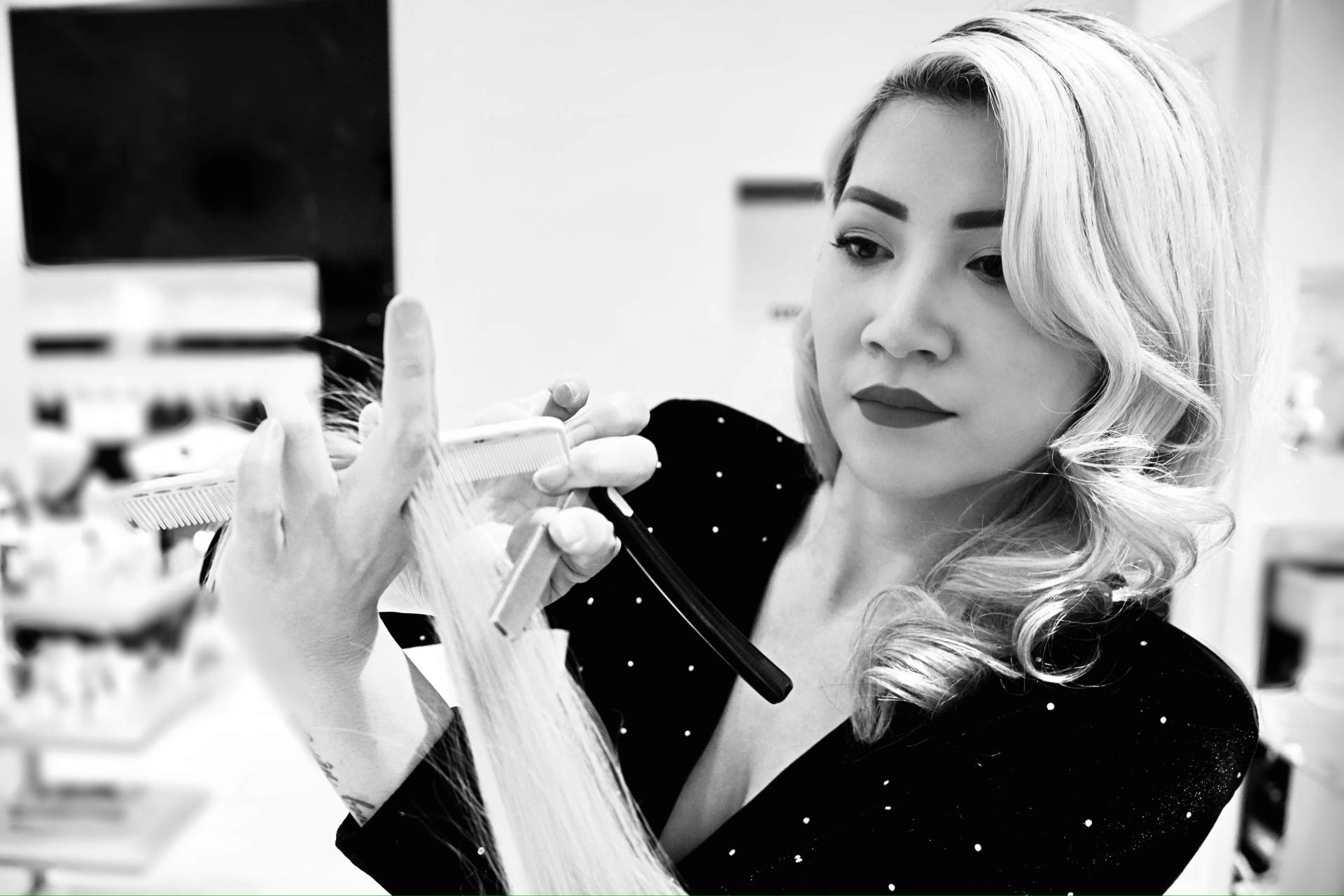 A black and white photo of a woman applying makeup.