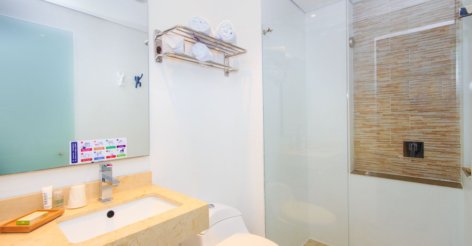 Baño con paredes blancas, lavabo, inodoro, ducha y toallero.