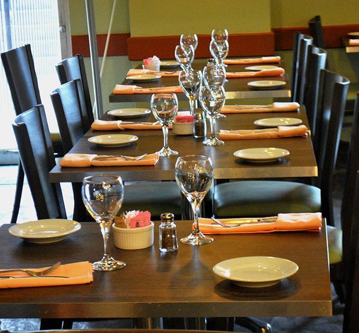 a row of tables with plates and wine glasses on them