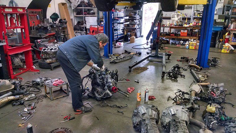 A man is working on a car engine in a garage