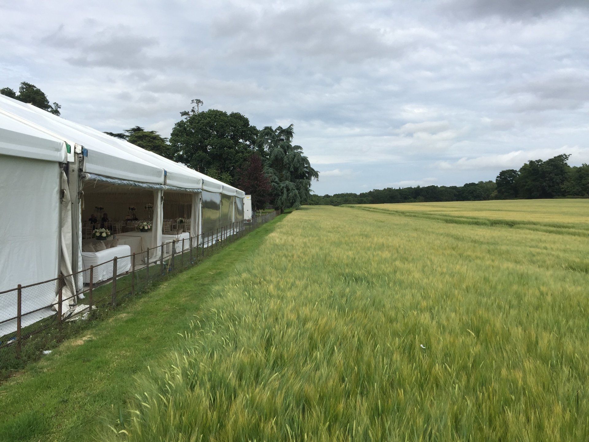 White event tents beside a green field under a cloudy sky