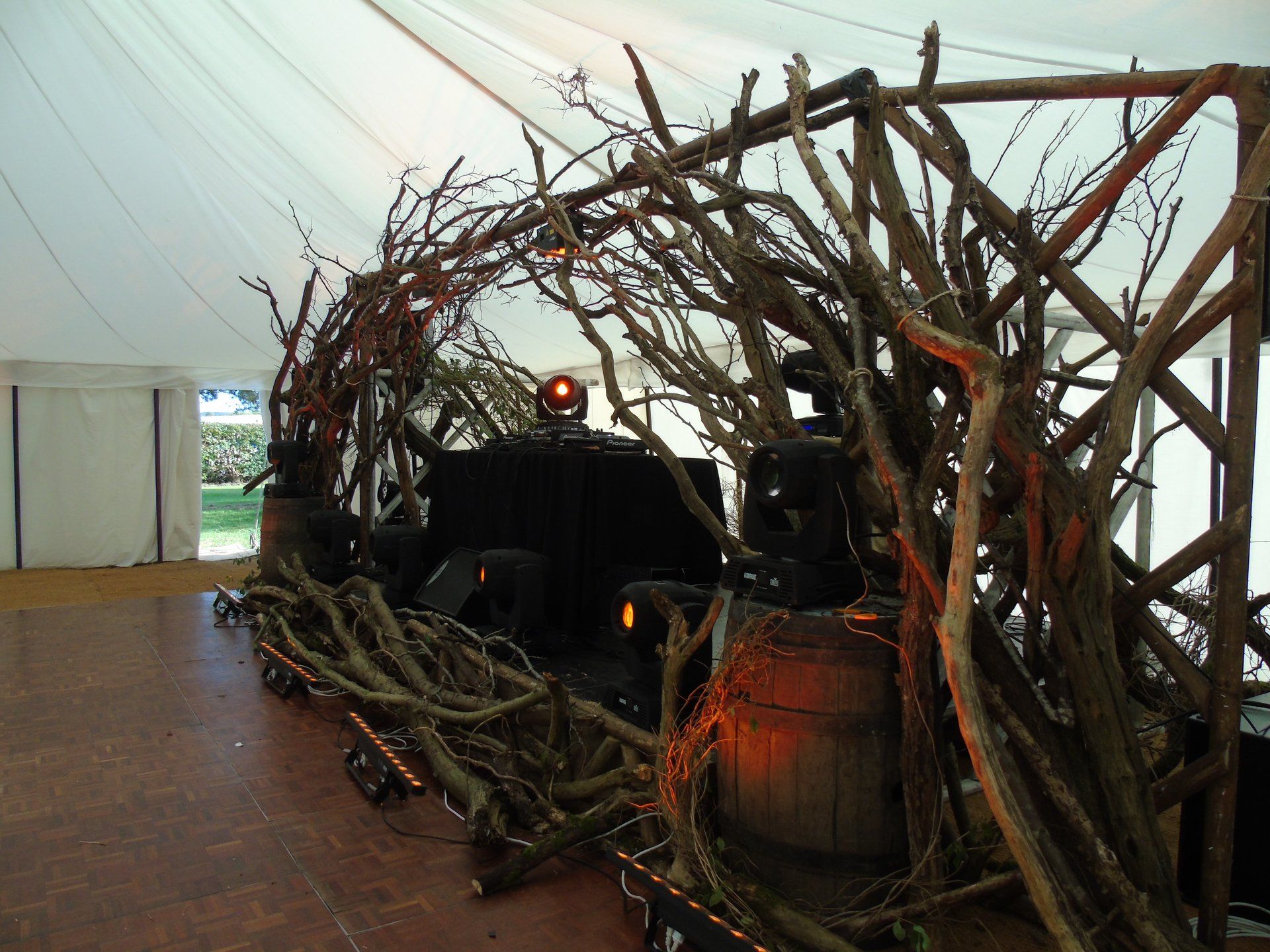 Twig-covered sculpture in an indoor gallery, with dark machinery and warm orange lights inside