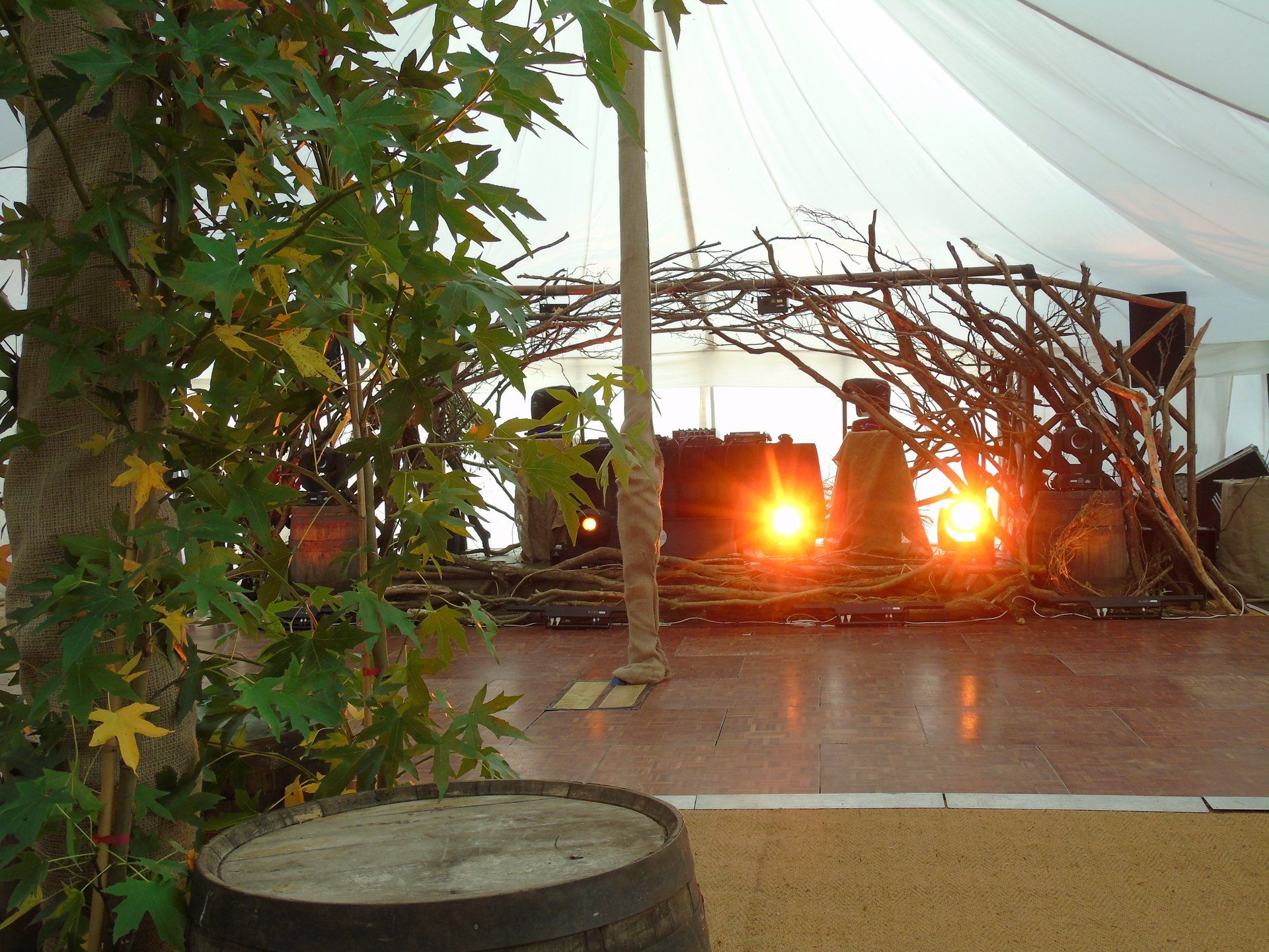 Sunset view through a woven branch structure with warm lights on a covered patio