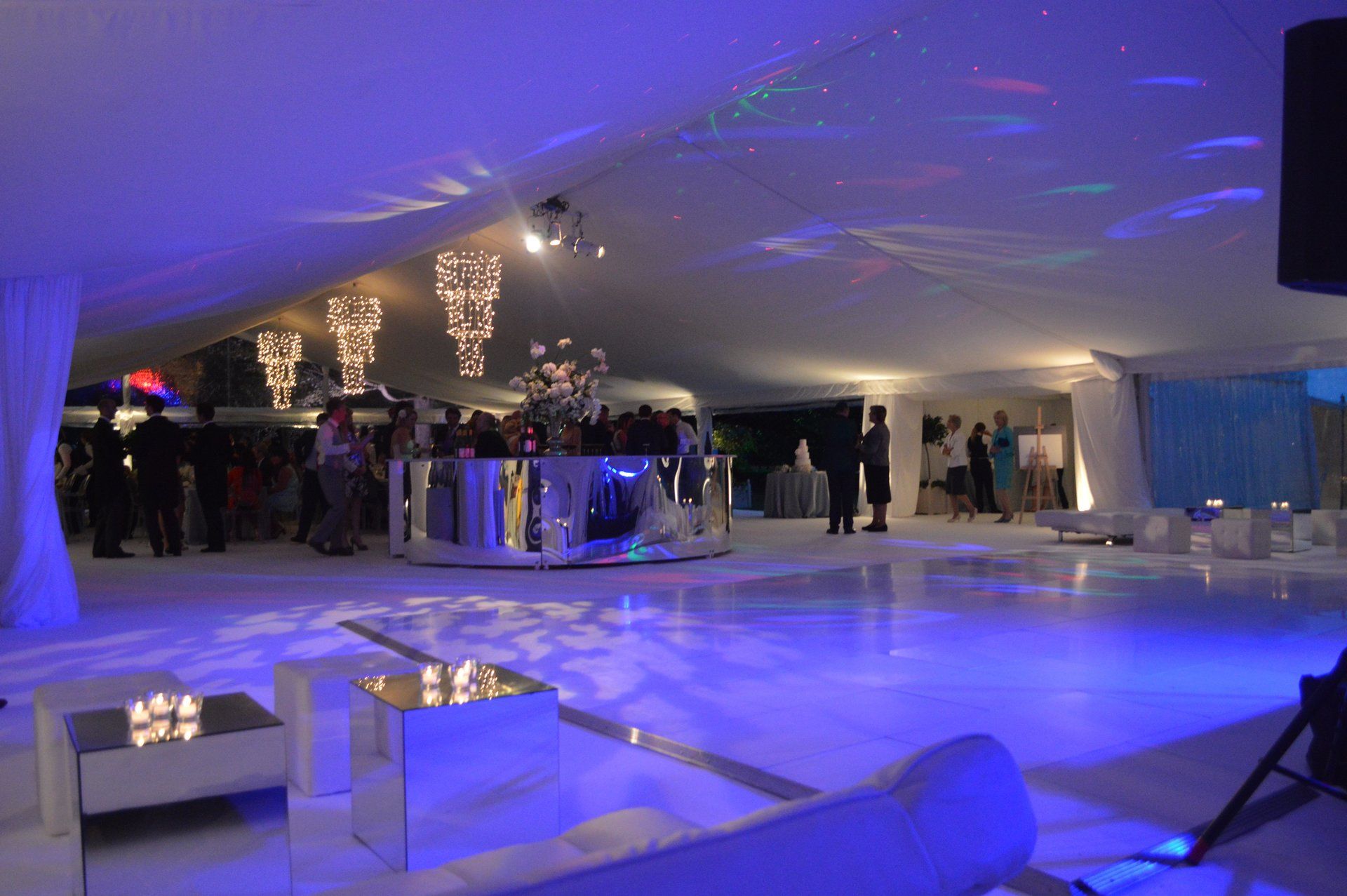 Elegant nightclub lounge with blue lighting, bar, and seated guests on a white floor
