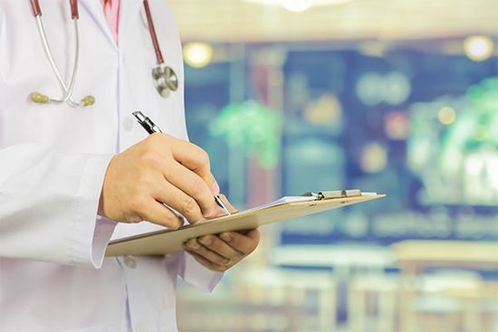 medico di sesso maschile con stetoscopio sul corridoio ospedale azienda appunti e scrivere una prescrizione