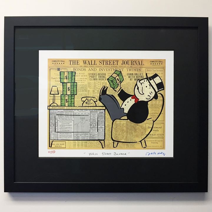 Rich Uncle Pennybags sits in a chair with feet on a desk atop The Wall Street Journal, holding a stack of cash.
