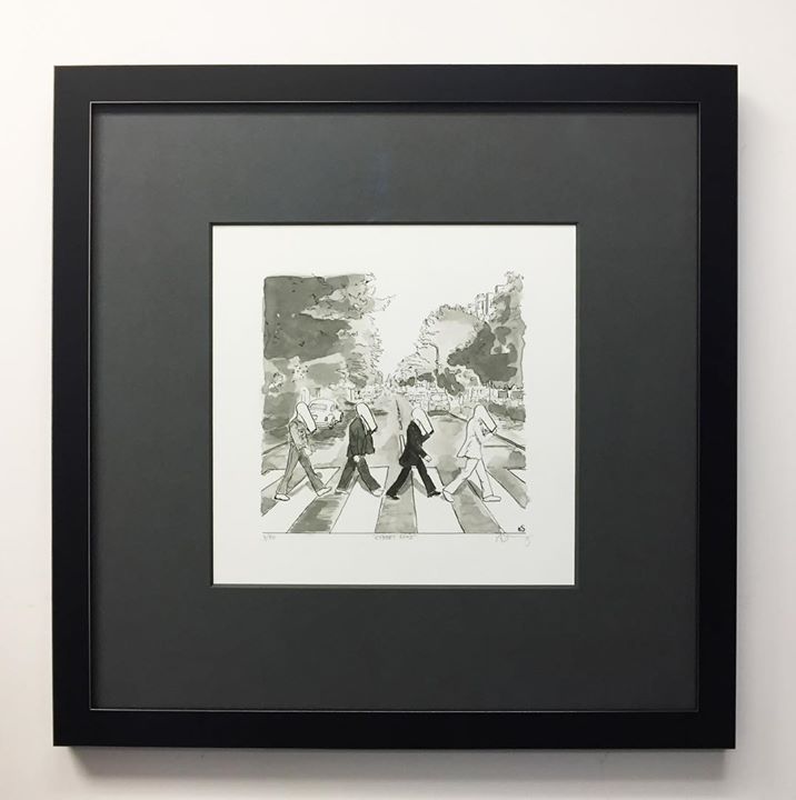 A framed black-and-white print of four figures walking across a crosswalk, referencing The Beatles’ Abbey Road album cover.
