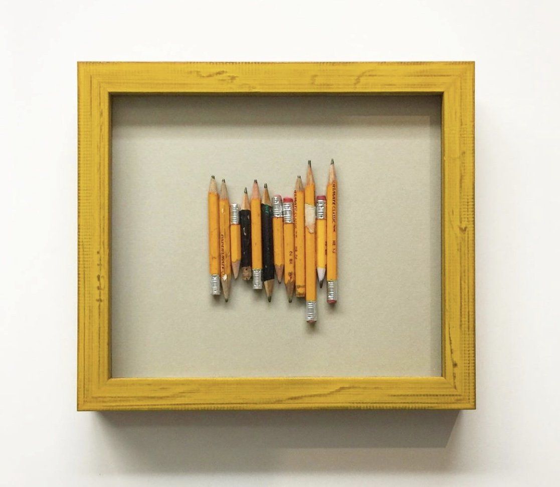 A collection of yellow pencil stubs arranged vertically inside a square, yellow wooden frame against a light background.