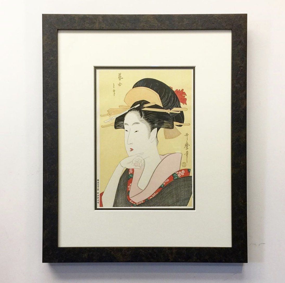 A framed Japanese ukiyo-e print featuring a person in traditional dress, dark hair, and a neutral expression.
