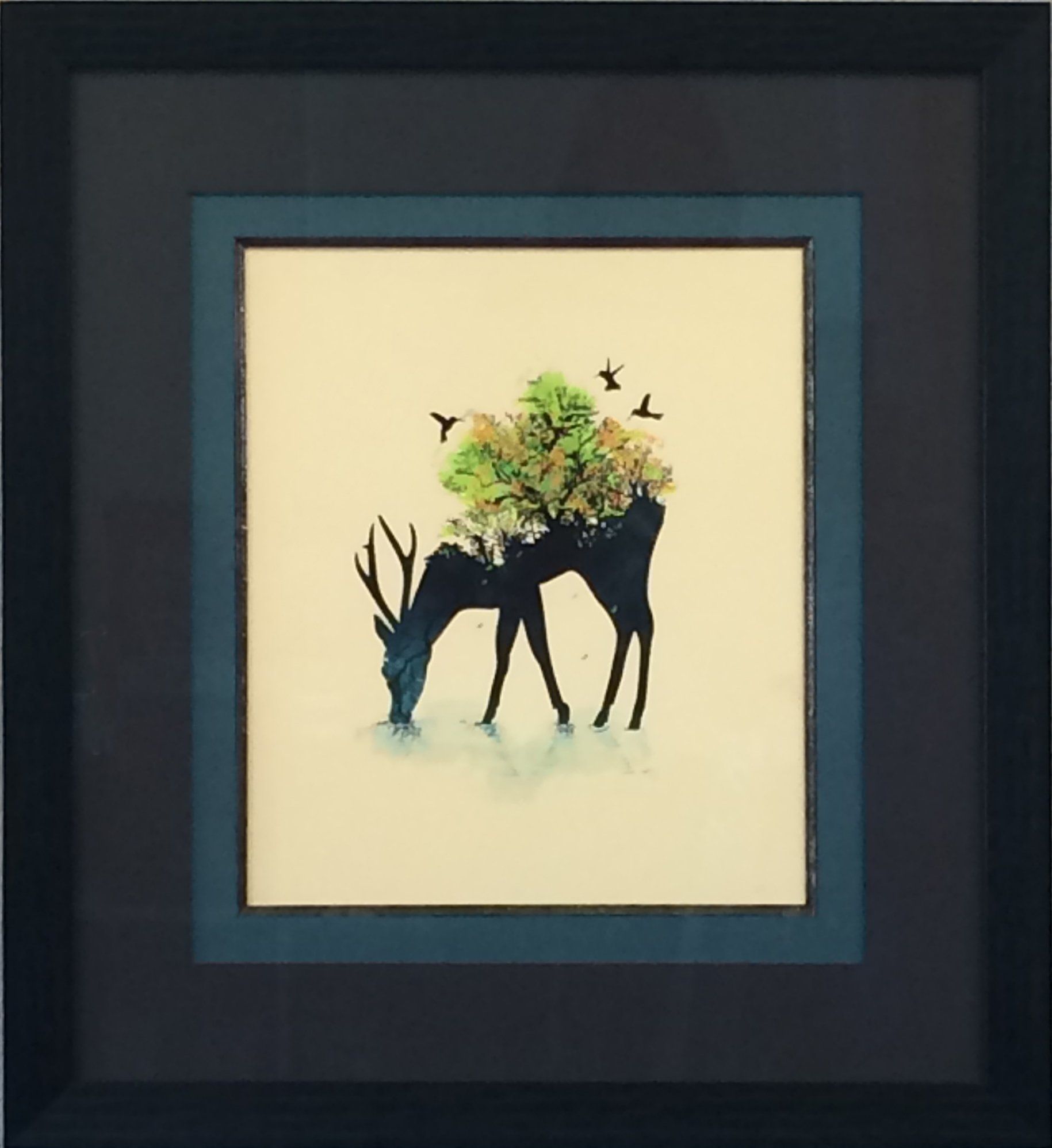 A framed art piece showing a black deer silhouette with vibrant green foliage on its back, set against a cream background.