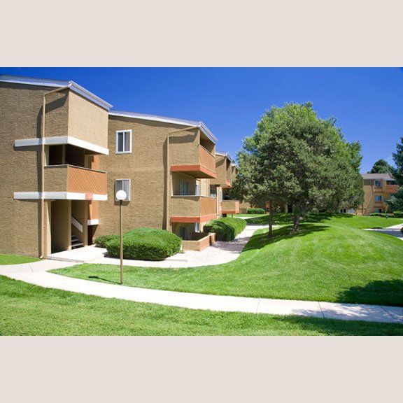 Apartment building with sidewalks next to it and green grass
