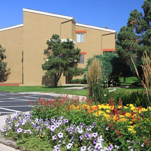 Apartment building and parking lot with an area full of flowers