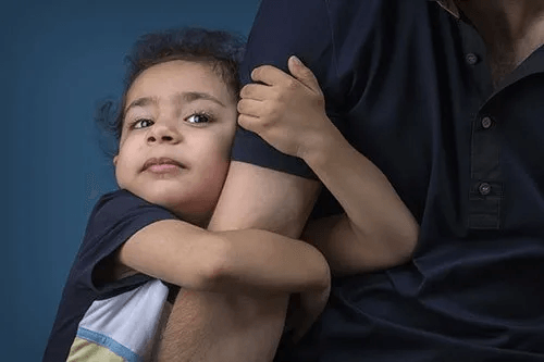 A son hugging his father's arm