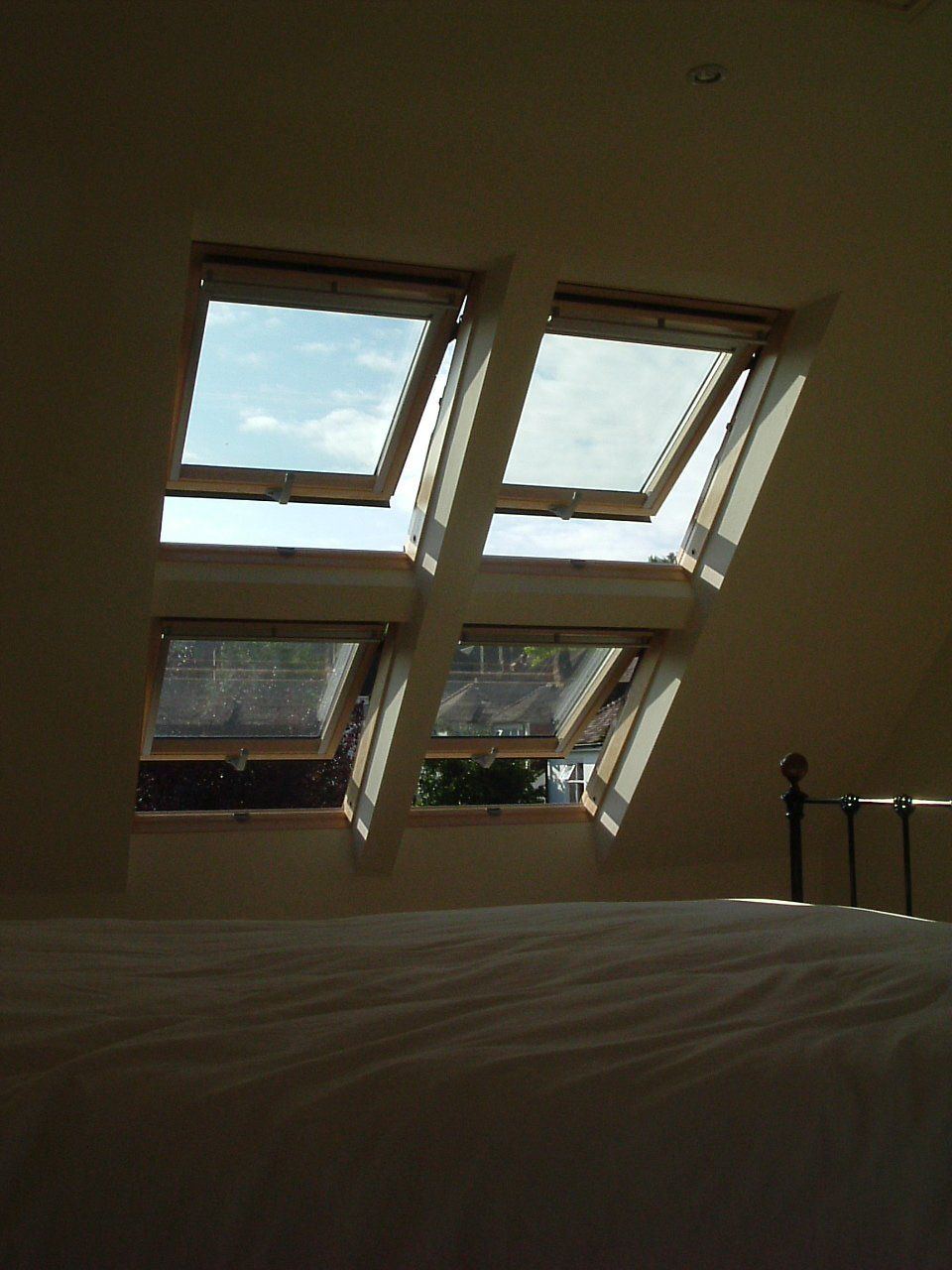 A bedroom with three skylights and a bed