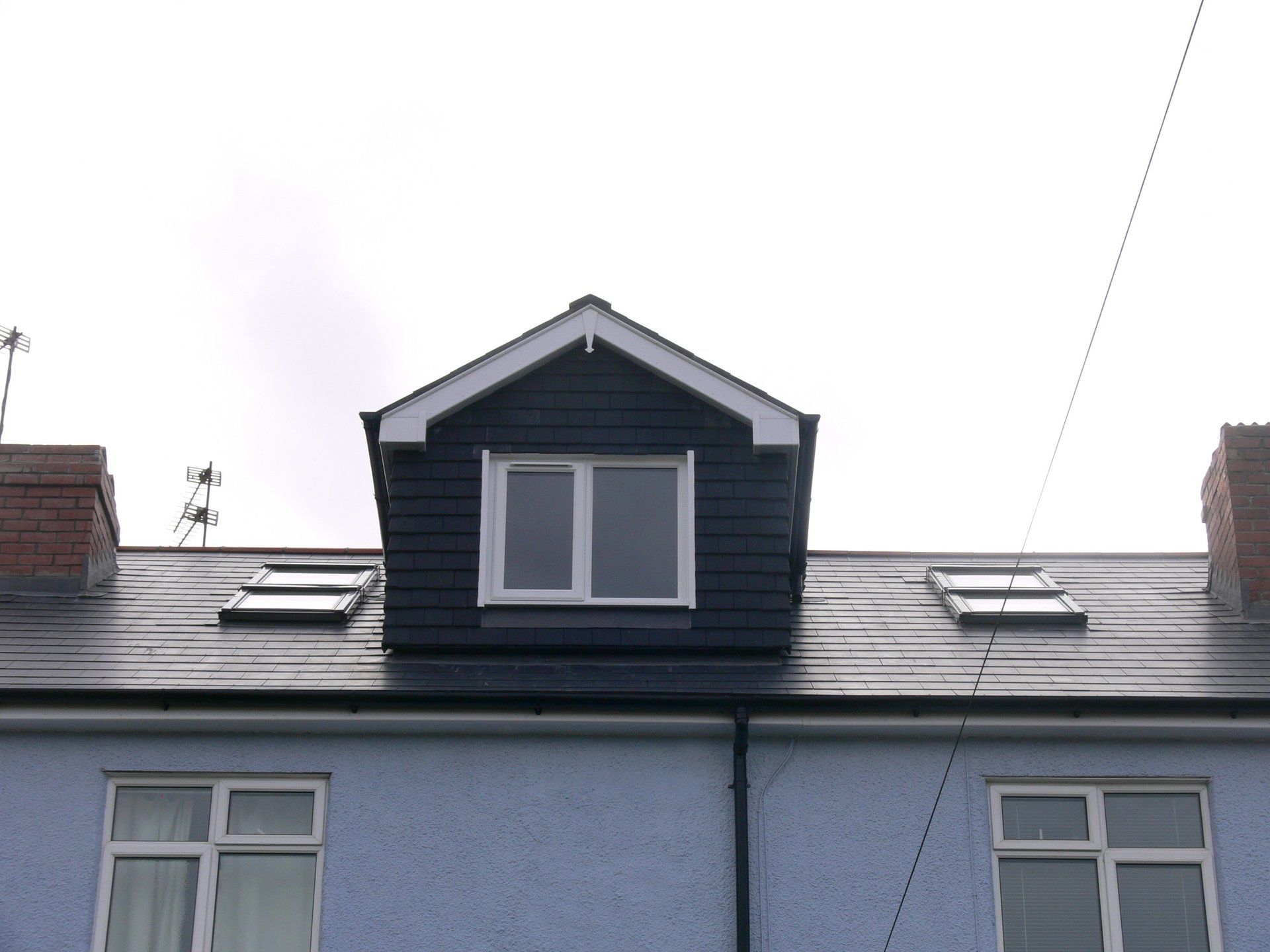 A blue house with a black roof and two windows