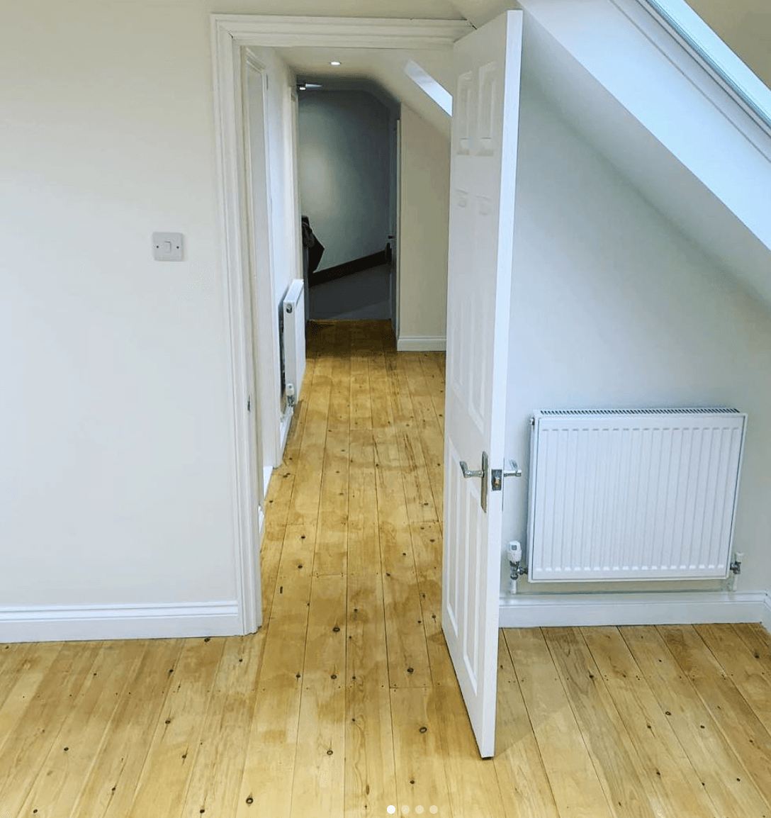 An empty loft room with wooden floors and white walls