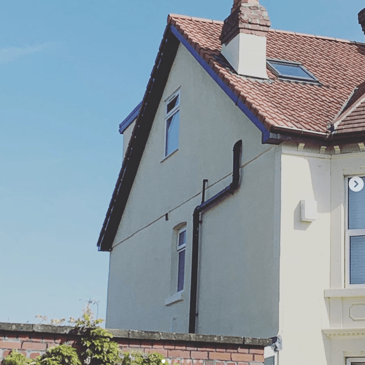 A white house with a brown roof and a blue trim