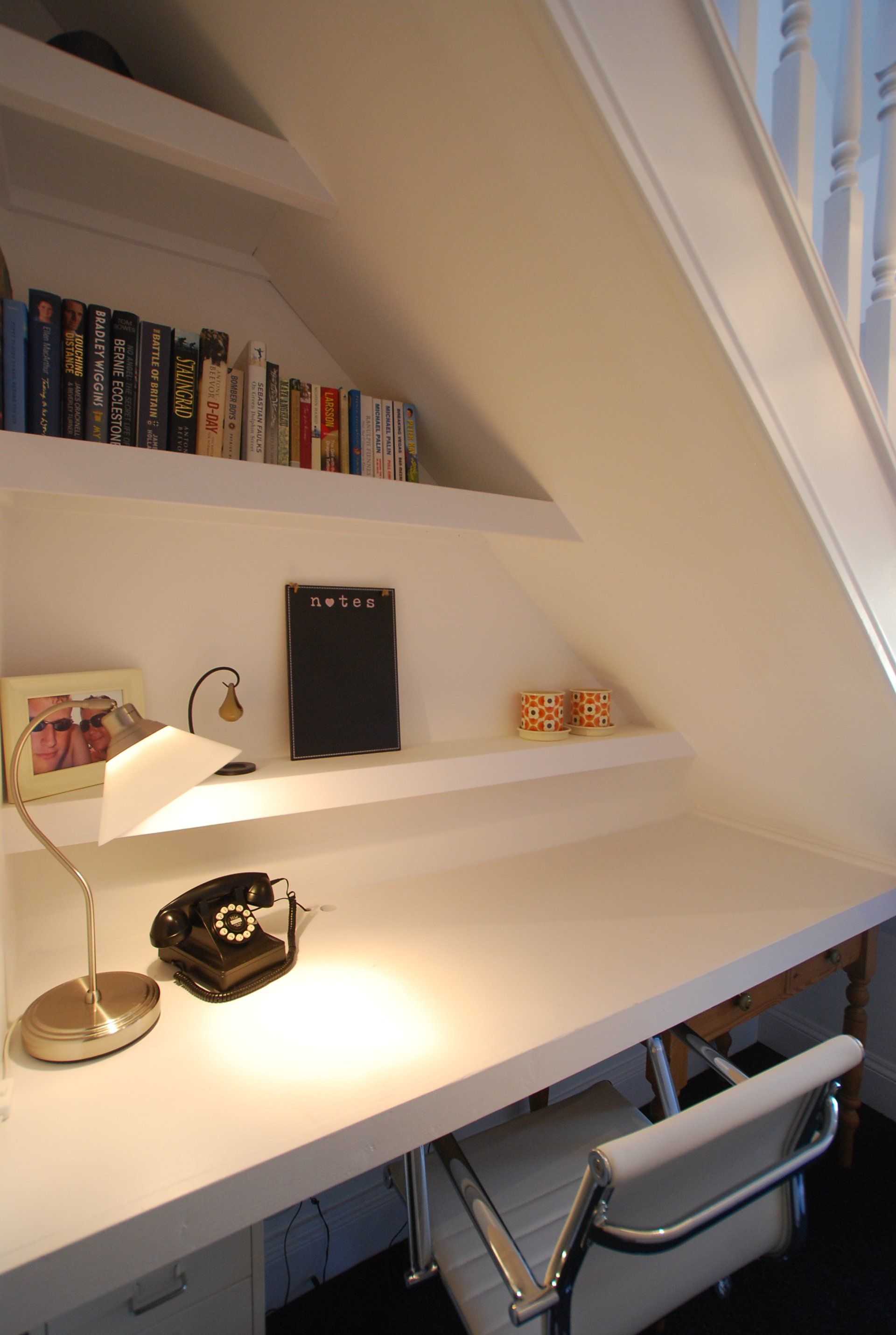 A white desk with a lamp and a phone on it