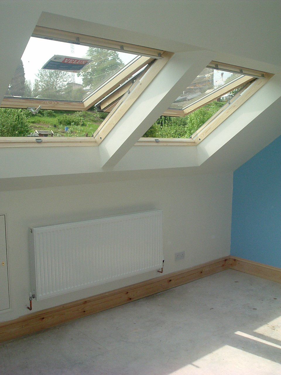 An empty room with two Velux skylights and a radiator