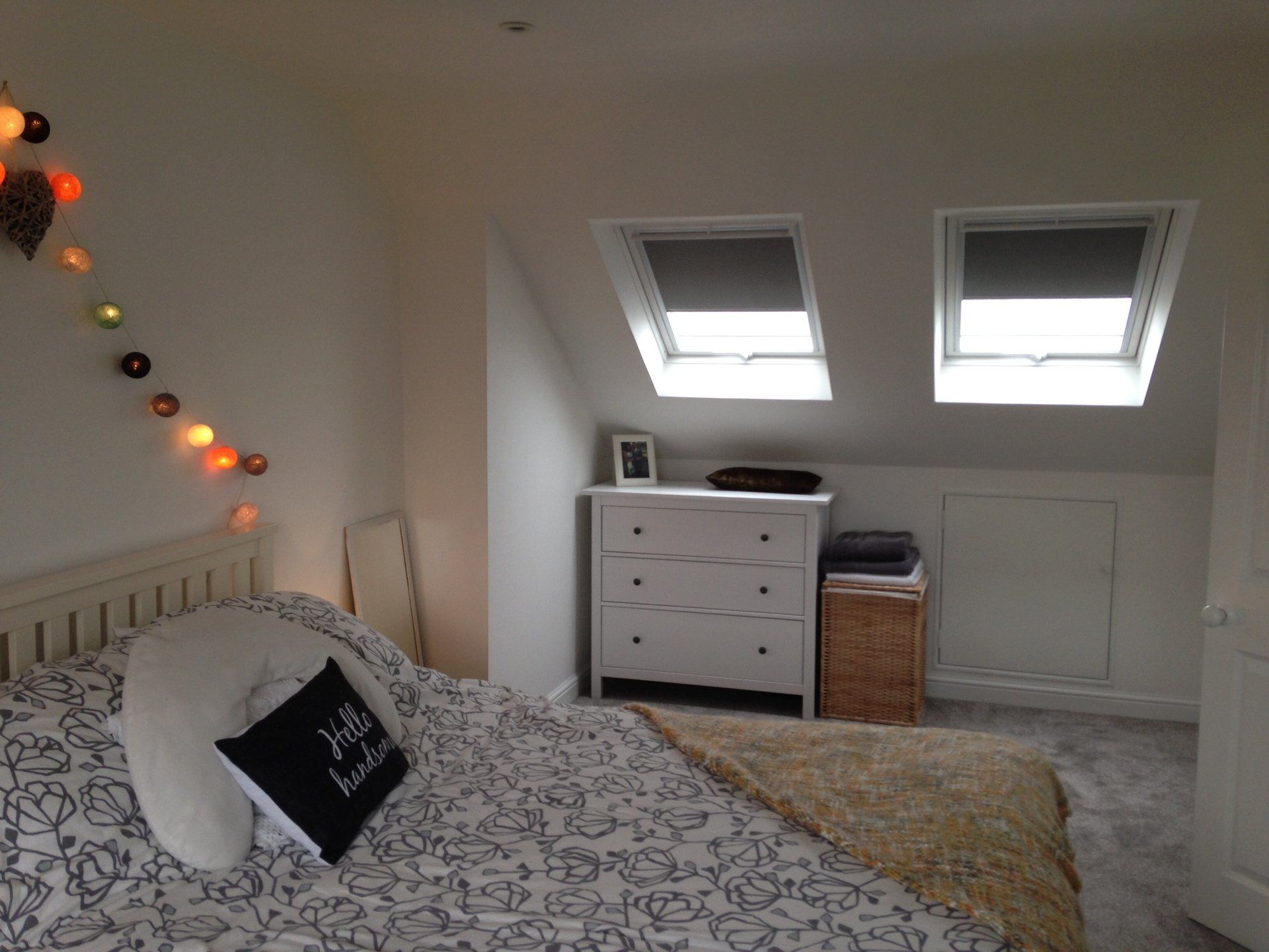 A bedroom with a bed a dresser and a skylight